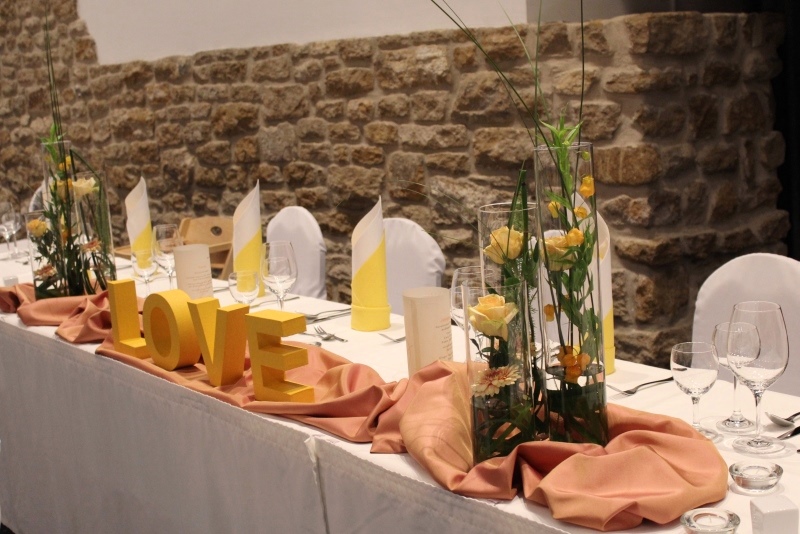 Der Brauttisch: Eine Tafel mit 2 Zylindervasen-Arrangements, Dekostoff und dem Schriftzug "LOVE".