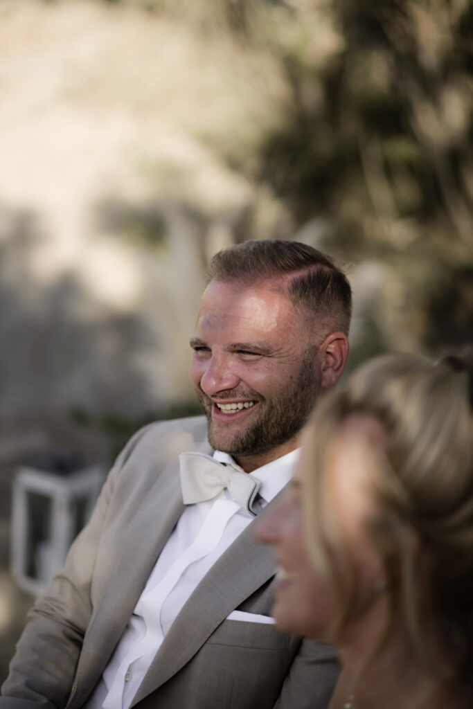 Bräutigam lacht bei Trau-Zeremonie am Strand auf Kreta