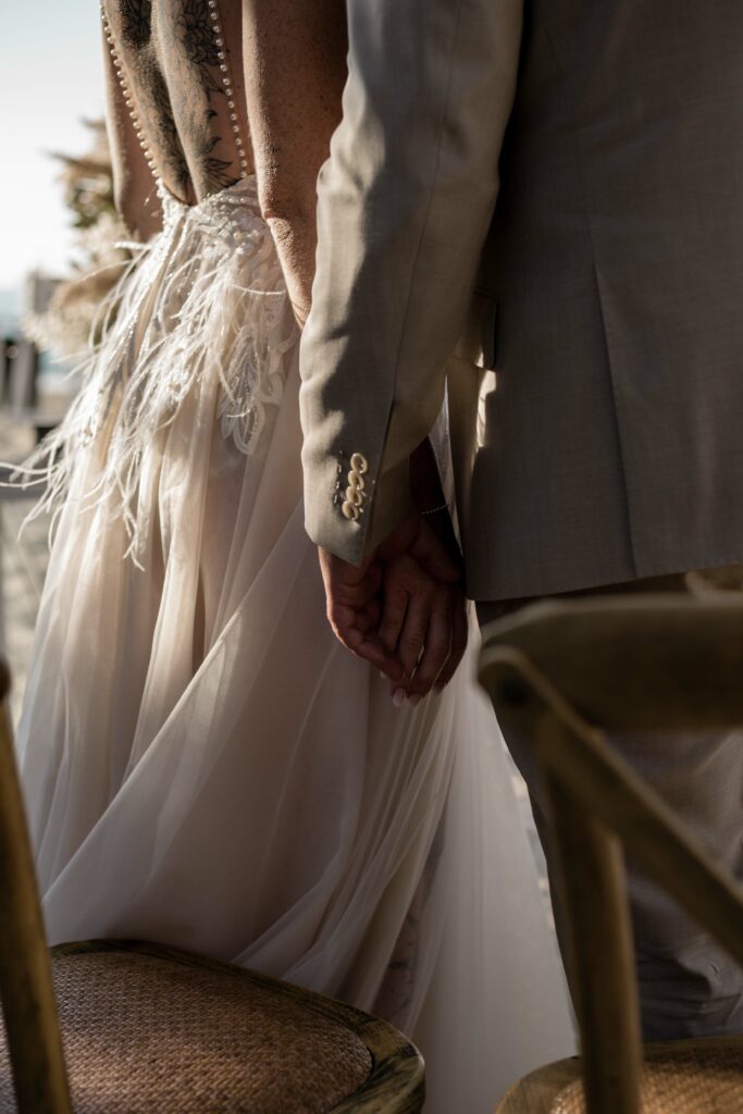 Brautpaar hält Händchen bei Trauung am Strand auf Kreta