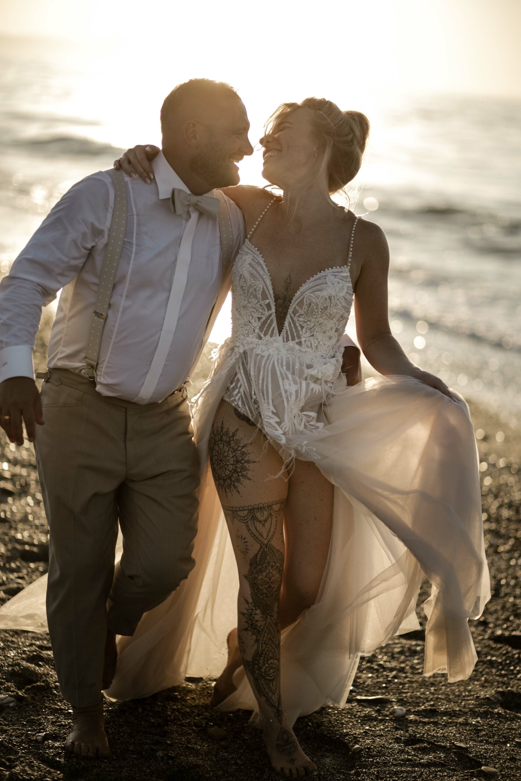 Brautpaar lacht verspielt am Meer zum Sonnenuntergang auf Kreta